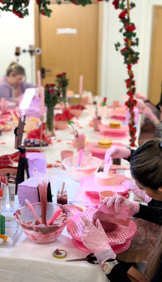 Decorating a mini cake with buttercream at a busy workshop table